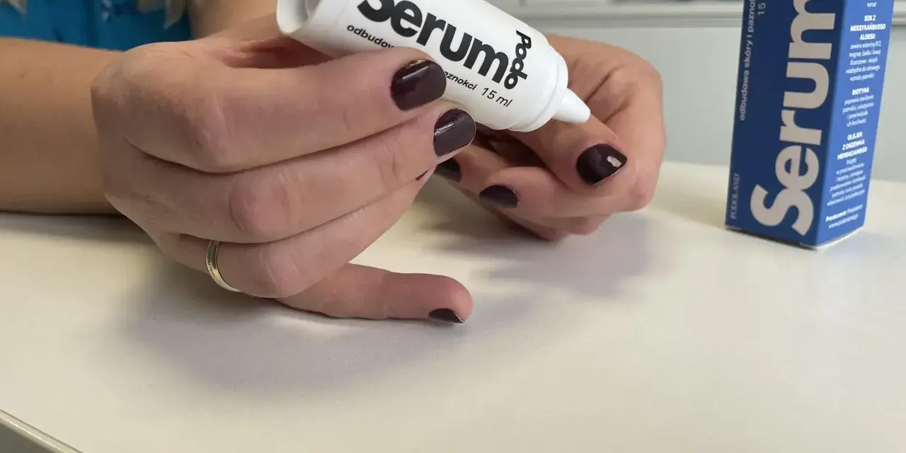 Dłonie z ciemnym lakierem aplikują podoserum na paznokieć. Opakowanie Podo Serum widoczne obok.