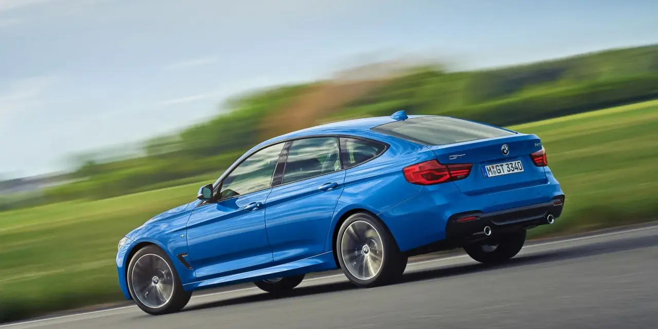 Niebieskie BMW 3 GT w ruchu, ukazujące jego sportowy profil. Warto rozważyć jego wady i zalety przed zakupem.