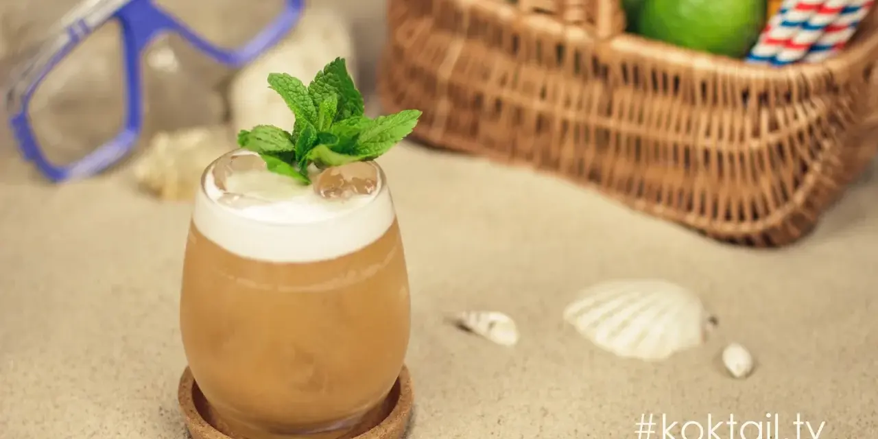 Orzeźwiający vodka sour z miętą na plaży, obok maska do nurkowania i koszyk z limonkami. Idealny na wakacje!