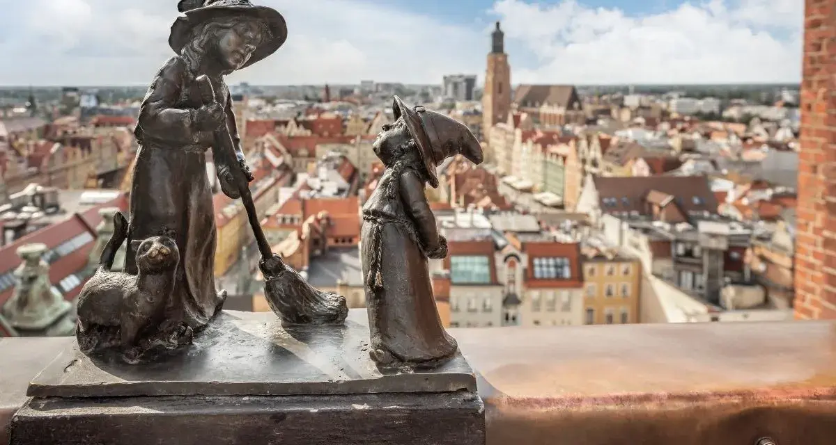 Dwa krasnale i kot na tle Wrocławia. Zastanawiasz się, ile jest krasnali we Wrocławiu?