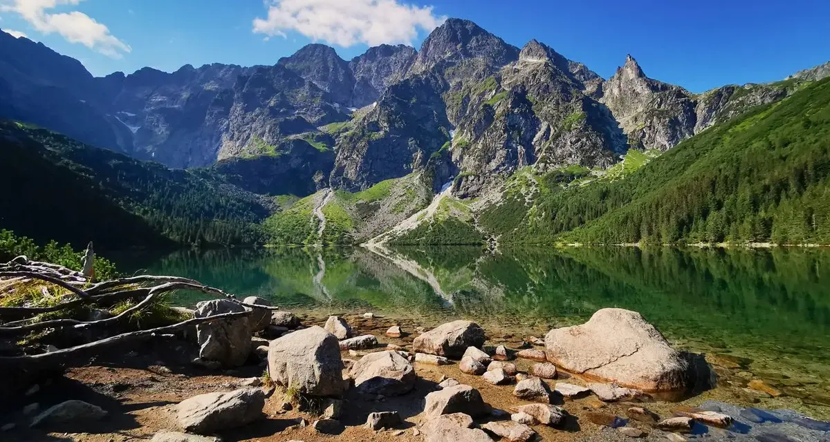 Kamienista plaża nad Morskim Okiem. W tle majestatyczne szczyty Tatrzańskiego Parku Narodowego odbijają się w krystalicznie czystej wodzie.