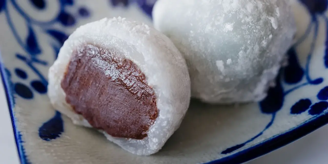 Pyszne mochi z czekoladowym nadzieniem, posypane cukrem pudrem. Idealne do domowego przepisu na mochi.