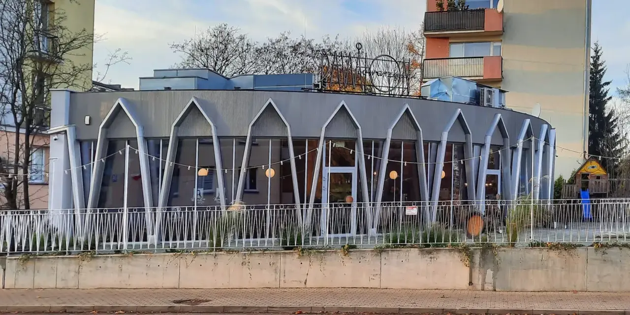 Charakterystyczna modernistyczna architektura budynku z przeszkloną fasadą i geometrycznymi elementami.