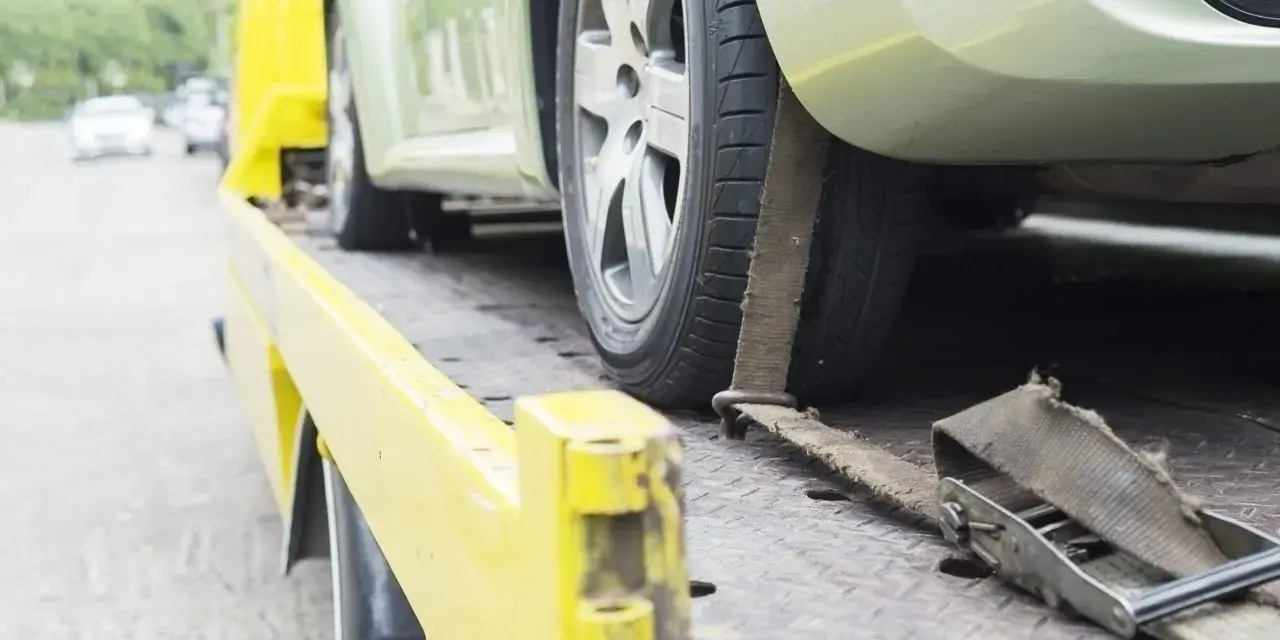 Czy komornik może zająć samochód osobie niepełnosprawnej? Auto na lawecie, zabezpieczone pasami.