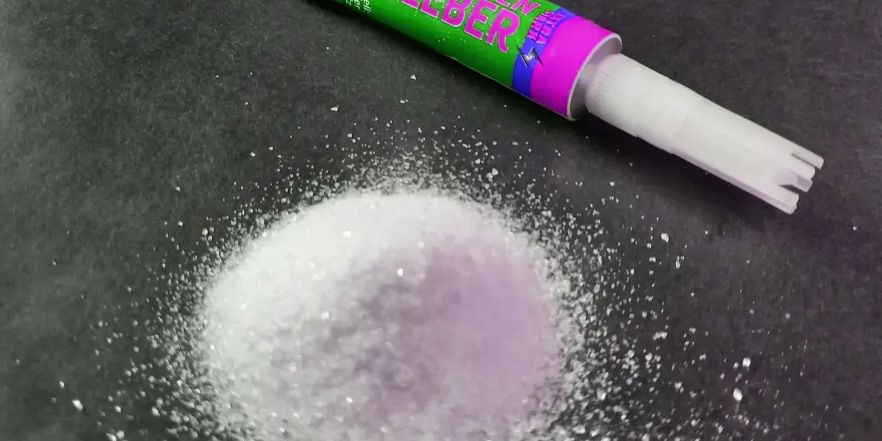 A pile of white granular material sits next to a tube of "Sekunden Kleber" super glue, ready for a quick fix.