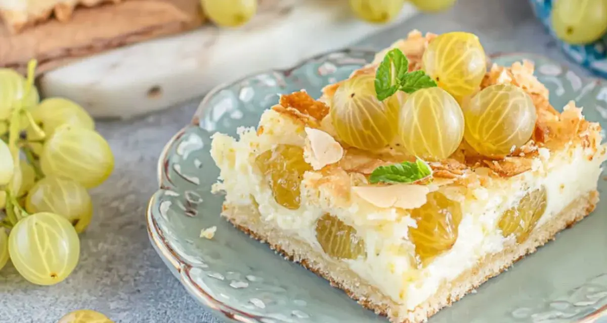 Ein Stück von die besten stachelbeerkuchen, garniert mit frischen Stachelbeeren und Mandelsplittern, auf einem zartblauen Teller.