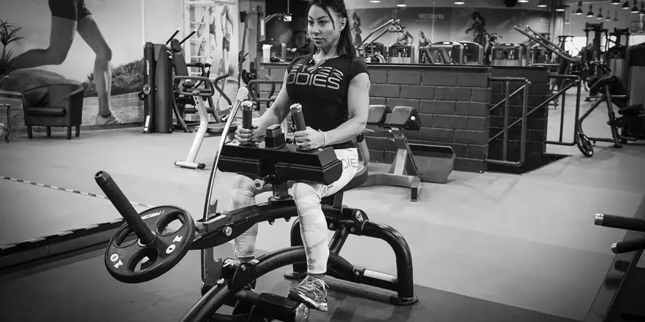Kvinna tränar sittande vadpress på gym.