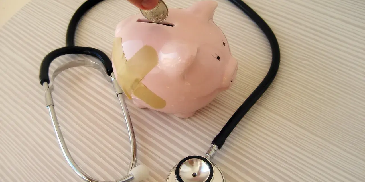 Salvadanaio a forma di maialino con cerotti, uno stetoscopio e una mano che inserisce una moneta. Simboleggia il dottore stipendio e la cura delle finanze.