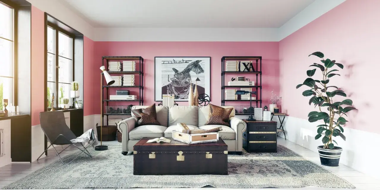 Salon z róż indyjski na ścianach. Wygodna sofa, stylowa skrzynia i regały pełne książek tworzą przytulną atmosferę.