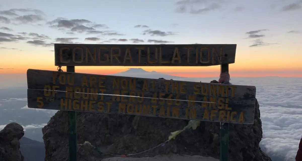 Gratulacje! Jesteś na szczycie Mount Meru, 5. najwyższej góry Afryki. Widok na morze chmur i wschód słońca zapiera dech w piersiach.