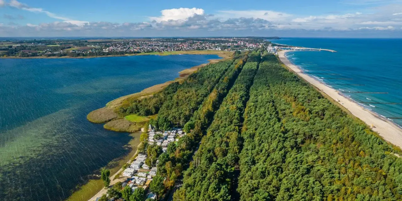 Półwysep Helski widziany z lotu ptaka: las sosnowy, plaża, morze i zatoka. Widać też miasteczko i kemping.