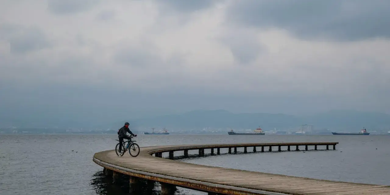 Rowerzysta przemierza malownicze trasy rowerowe nad morzem, podziwiając spokojną taflę wody i statki na horyzoncie.