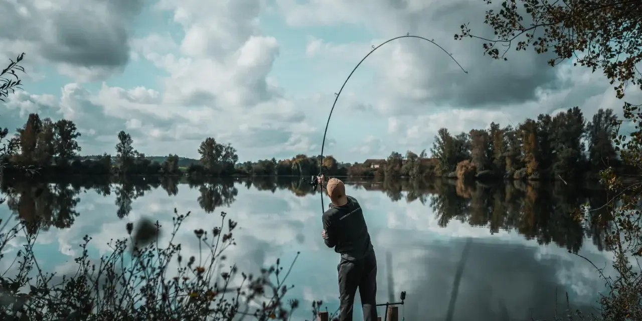 Wędkarz na pomoście, zgięta w łuk wędka świadczy o walce z rybą. Konopie na ryby to jego pasja.