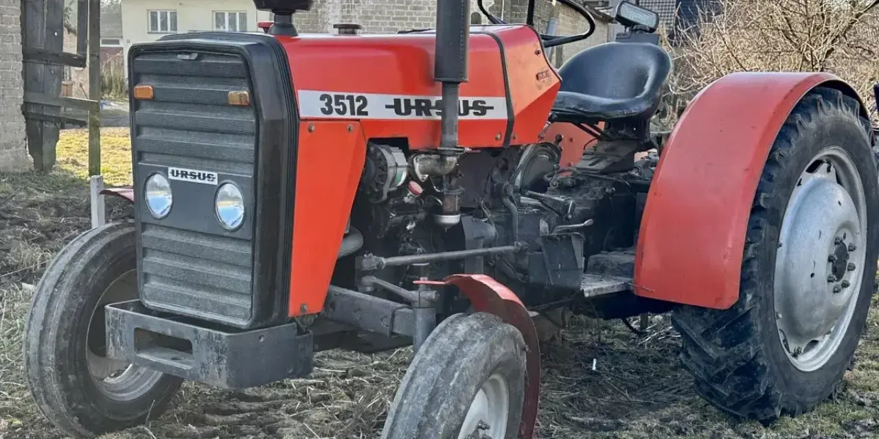 Czerwony ciągnik Ursus 3512 z czarną maskownicą i siedzeniem, stojący na ziemi.