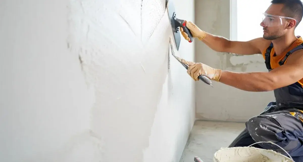 Artisan appliquant un enduit chaux sable intérieur à la taloche. Le mur prend forme, prêt pour une finition naturelle et saine.