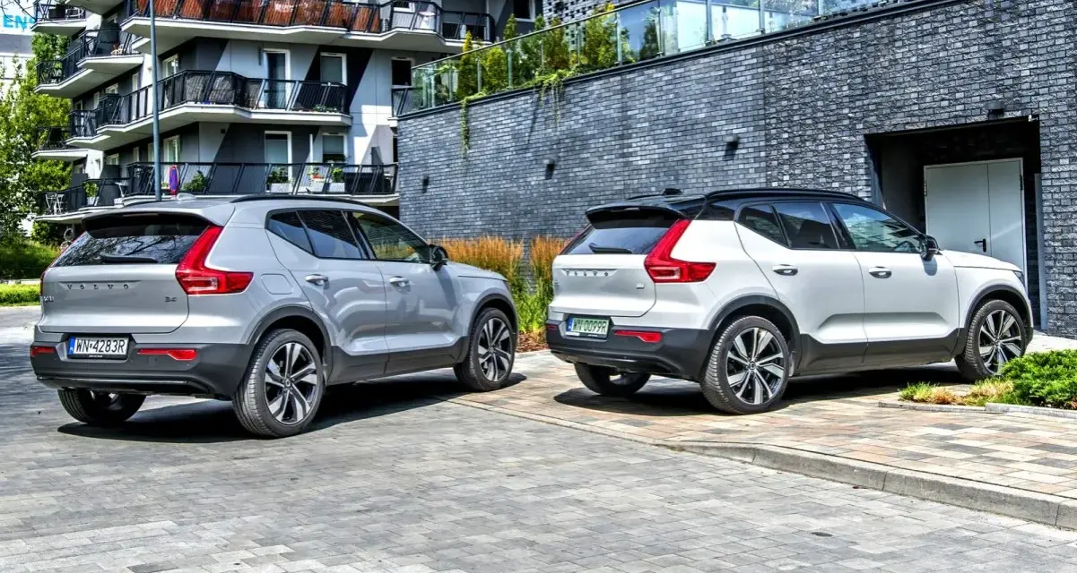 Dwa modele Volvo XC40, jeden srebrny, drugi biały, zaparkowane przed nowoczesnym budynkiem.