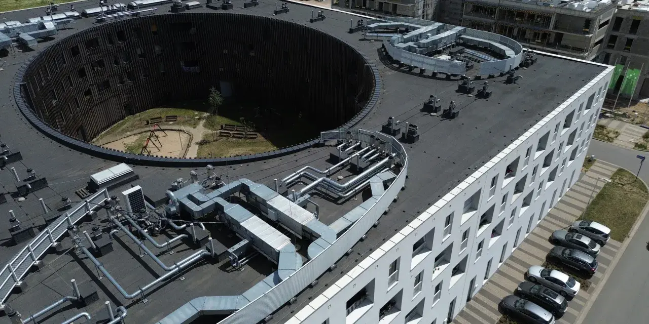 Nowoczesne budynki we Wrocławiu, z charakterystycznym okrągłym dziedzińcem i skomplikowaną instalacją wentylacyjną na dachu. Żerniki Wrocławskie w pełnej krasie.