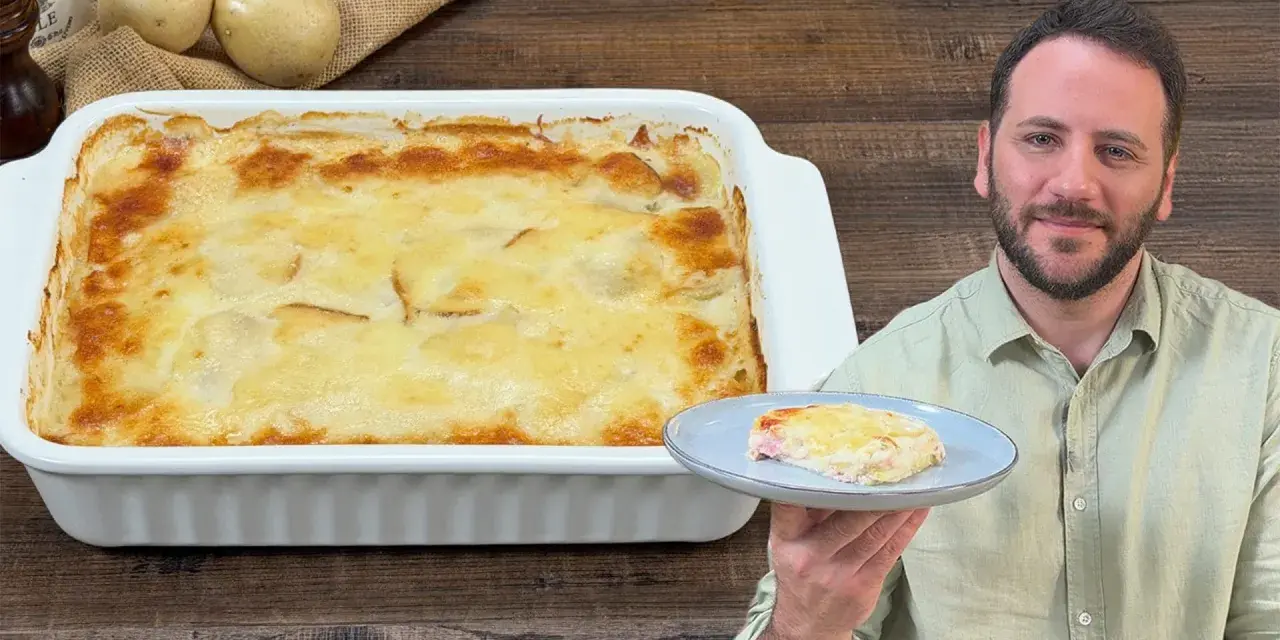 Un uomo sorride mostrando una fetta di parmigiana di patate appena sfornata, dorata e filante.