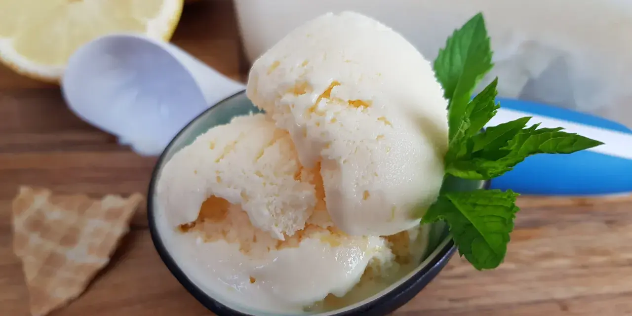 Erfrischendes zitronen joghurt eis mit Minze und einem Waffelstück auf Holztisch.