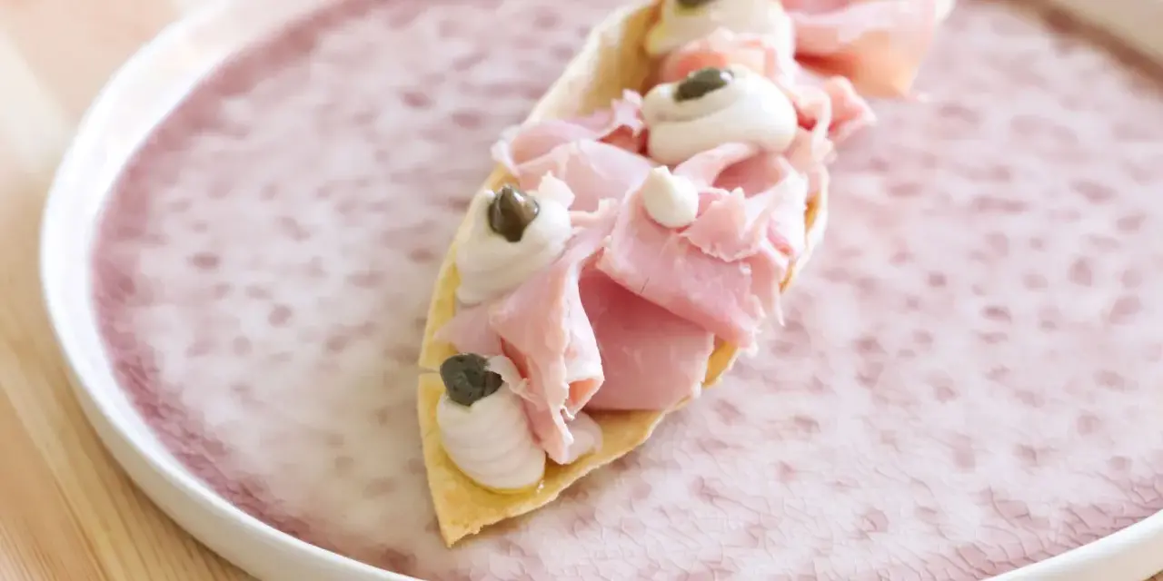 Delizioso antipasto con pane carasau, prosciutto cotto, crema e capperi. Un'idea per ricette veloci e gustose.