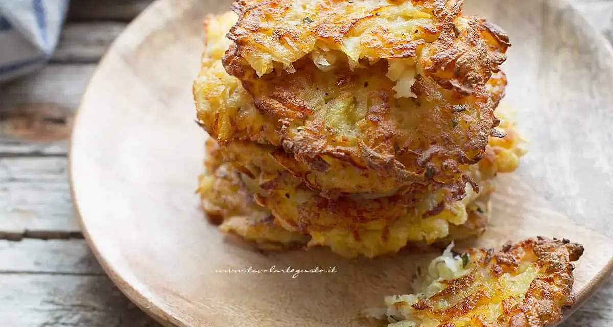 Una pila di dorate frittelle di patate, croccanti fuori e morbide dentro, servite su un piatto di legno.