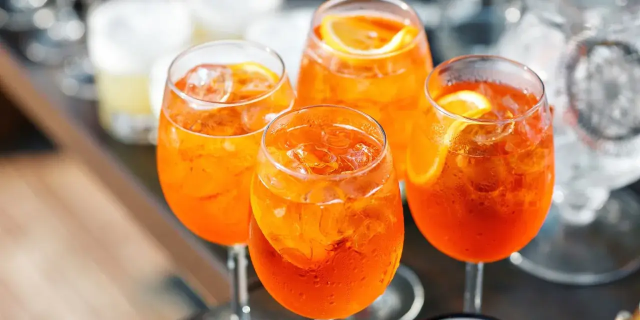 Cztery orzeźwiające drinki Aperol Spritz z lodem i plasterkami pomarańczy. Idealny aperol przepis na letnie popołudnie.