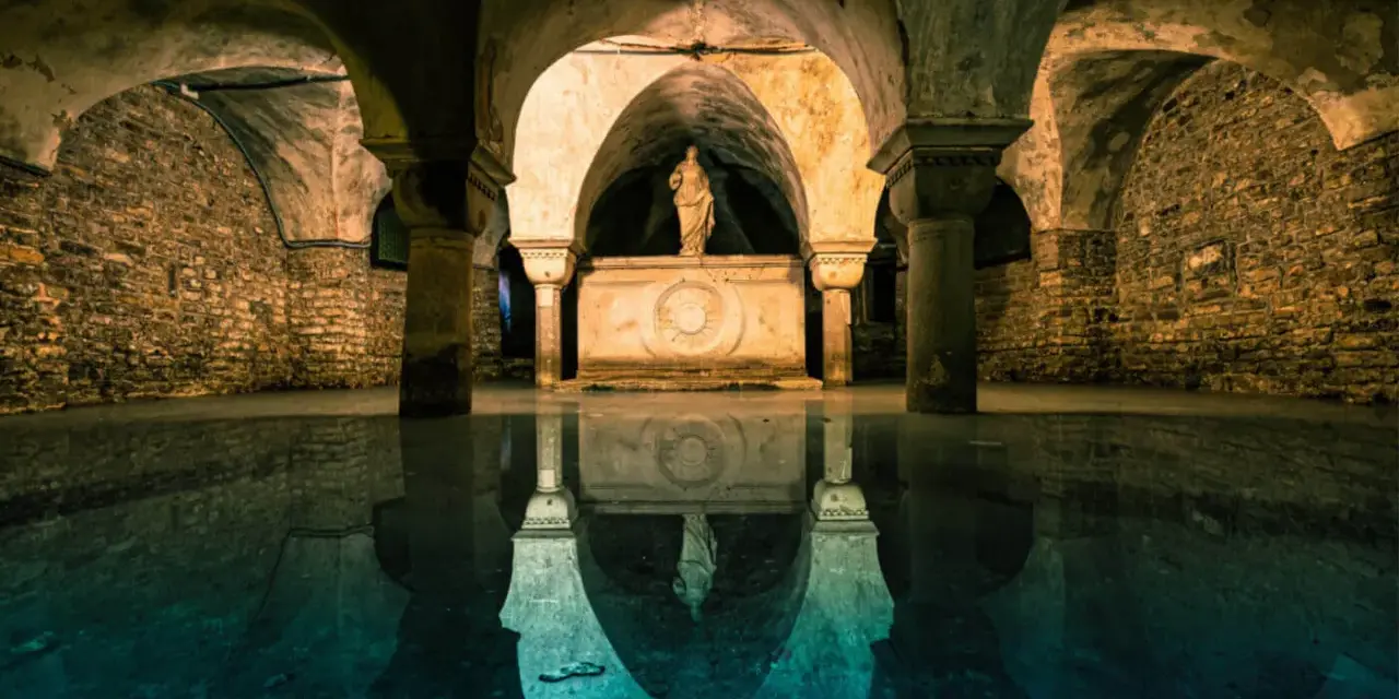 Sotterranei di Venezia misteriosa, con statue e riflessi sull'acqua.