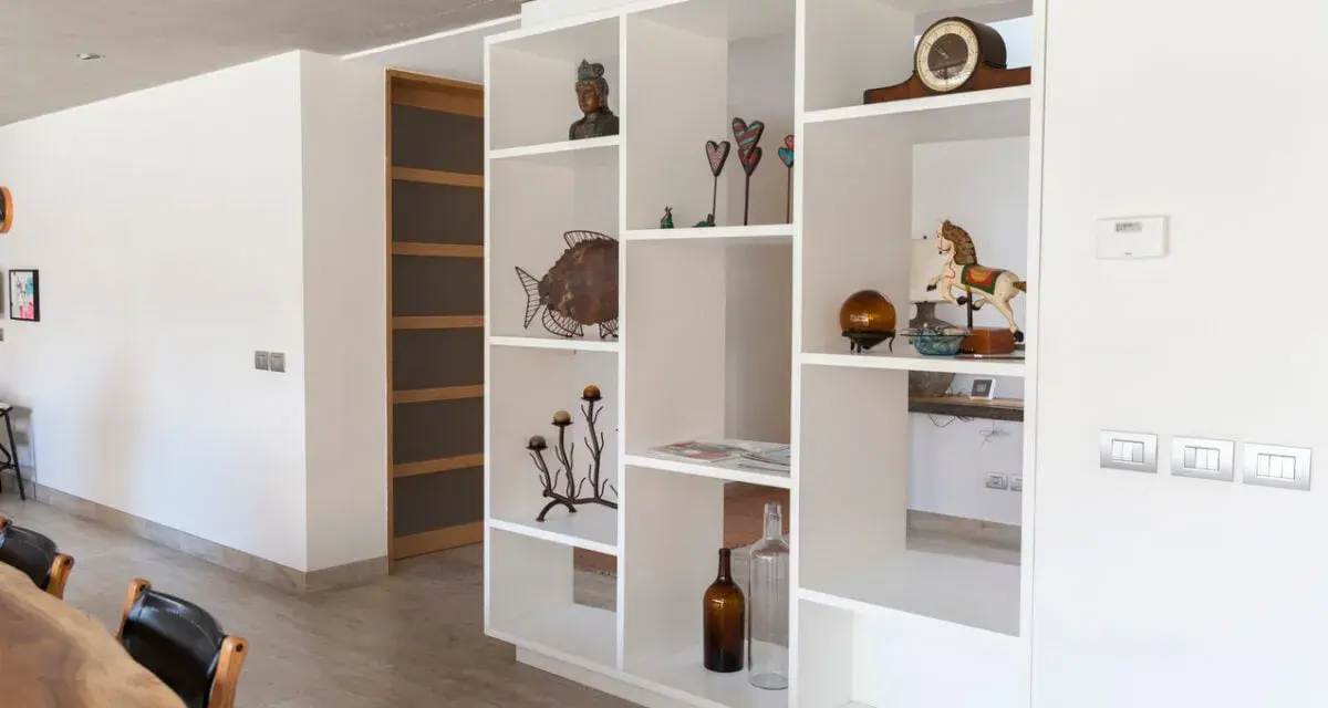 Libreria in cartongesso, perfetta come divisorio per l'ingresso, con oggetti decorativi e un cavallo a dondolo.