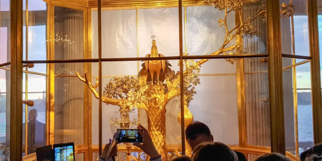 Złoty paw na drzewie w Muzeum Ermitaż. Zwiedzający robią zdjęcia tego wspaniałego zegara.