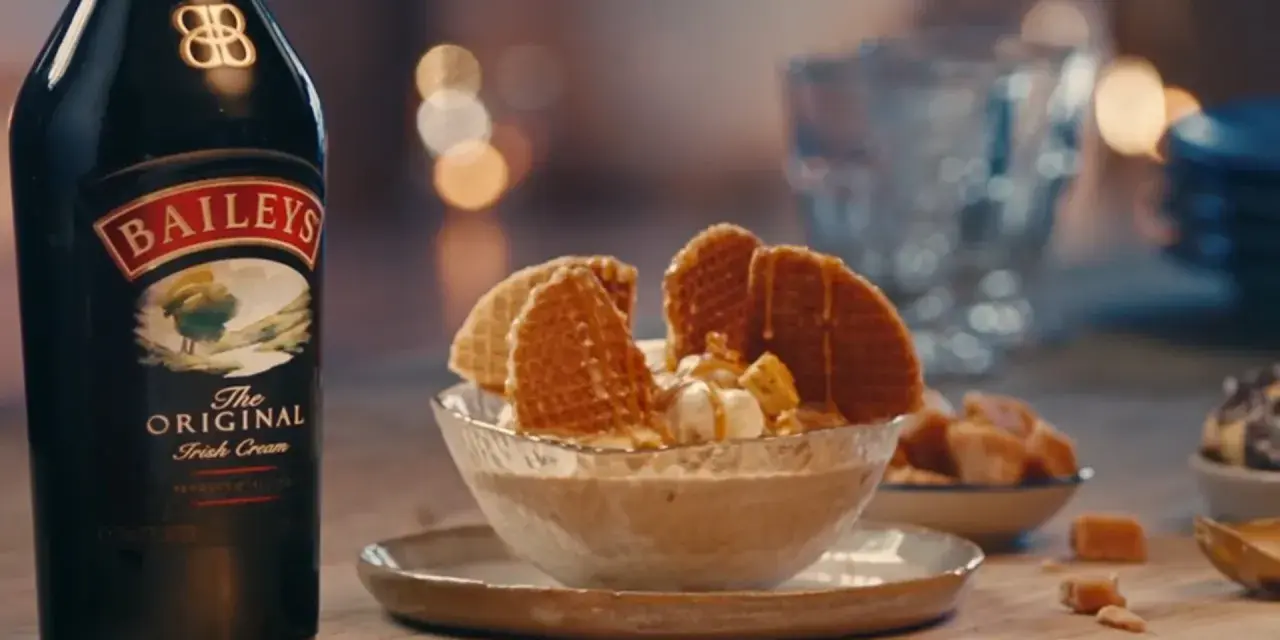 Baileys Eis Rezept: Cremiges Eis mit Karamell und Waffeln, daneben eine Flasche Baileys.