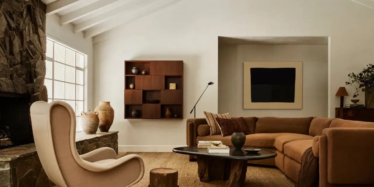 Un acogedor salón con chimenea de piedra, sillón de tela, sofá marrón y mesa de centro de madera. El arte de pared y las cerámicas añaden un toque de estilo chino hogar.