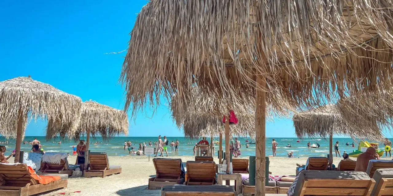 Słoneczny dzień na plaży w Rumunii nad Morzem Czarnym. Leżaki i parasole z trawy zapraszają do odpoczynku.