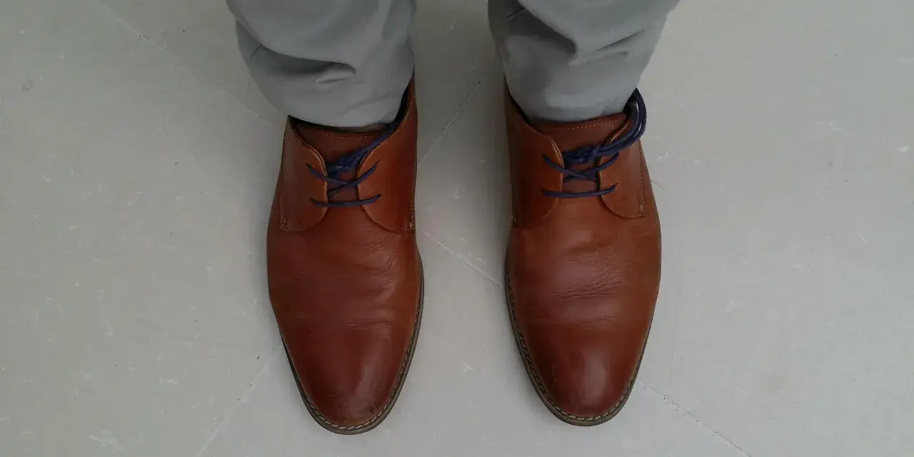 Scarpe marroni eleganti con lacci blu nascosti, un modo per allacciare le scarpe senza far vedere i lacci.