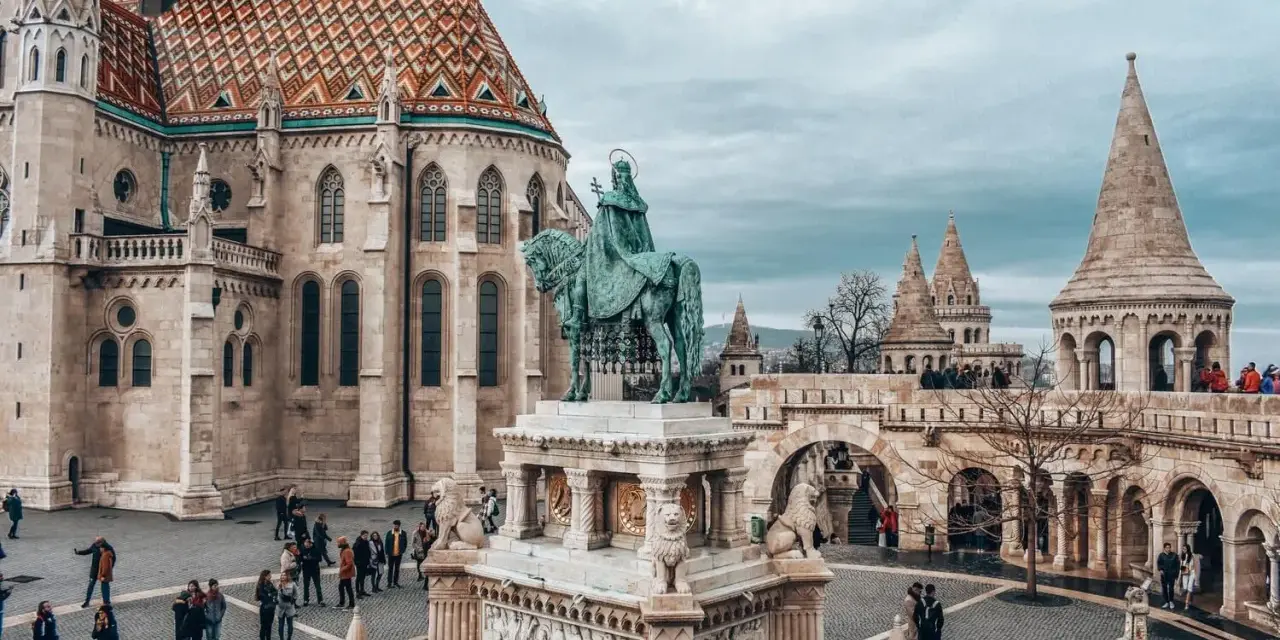 Budapeszt ceny: Rynek z pomnikiem konnym i Kościołem Macieja. Turyści zwiedzają zamek.
