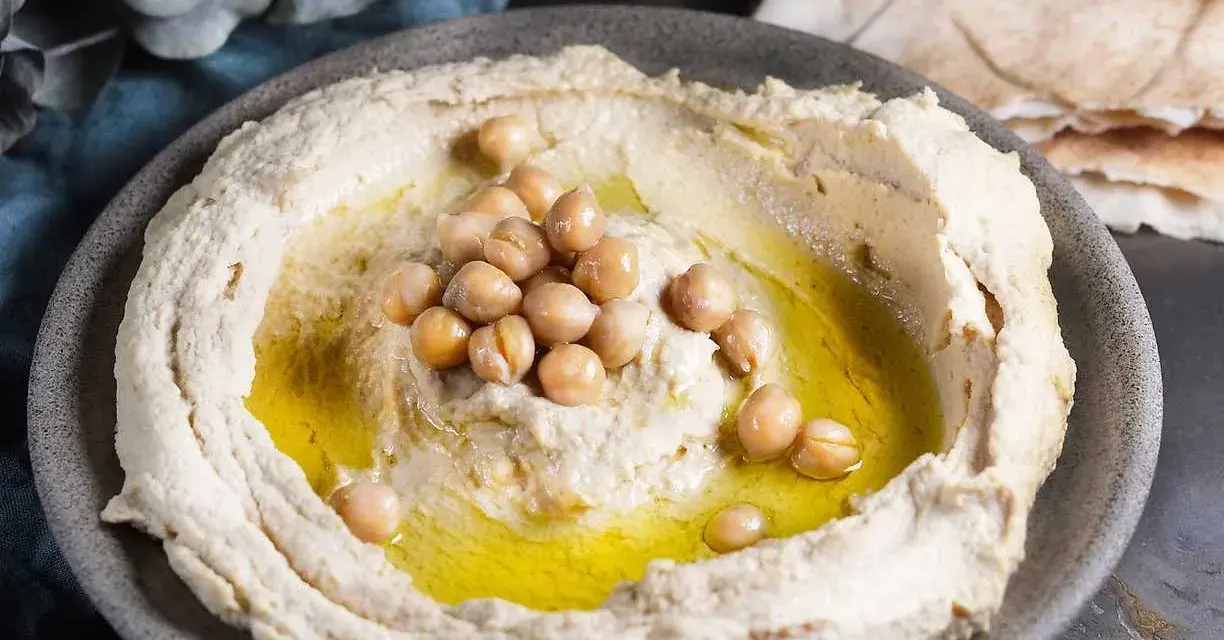 Krämig hummus med kikärtor och olivolja, perfekt för ett enkelt hummus recept. Serveras med pitabröd.