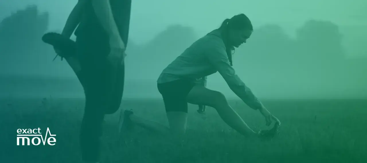 Två personer stretchar utomhus i dimma. En kvinna på knä sträcker sig mot sin fot. Detta kan vara en del av rehab benhinneinflammation.