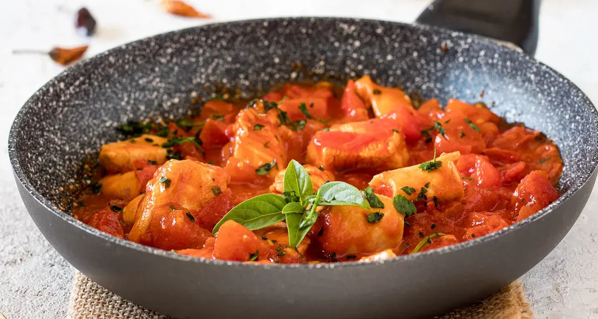Bocconcini di pollo in padella con pomodoro e basilico, un piatto succulento pronto per essere gustato.