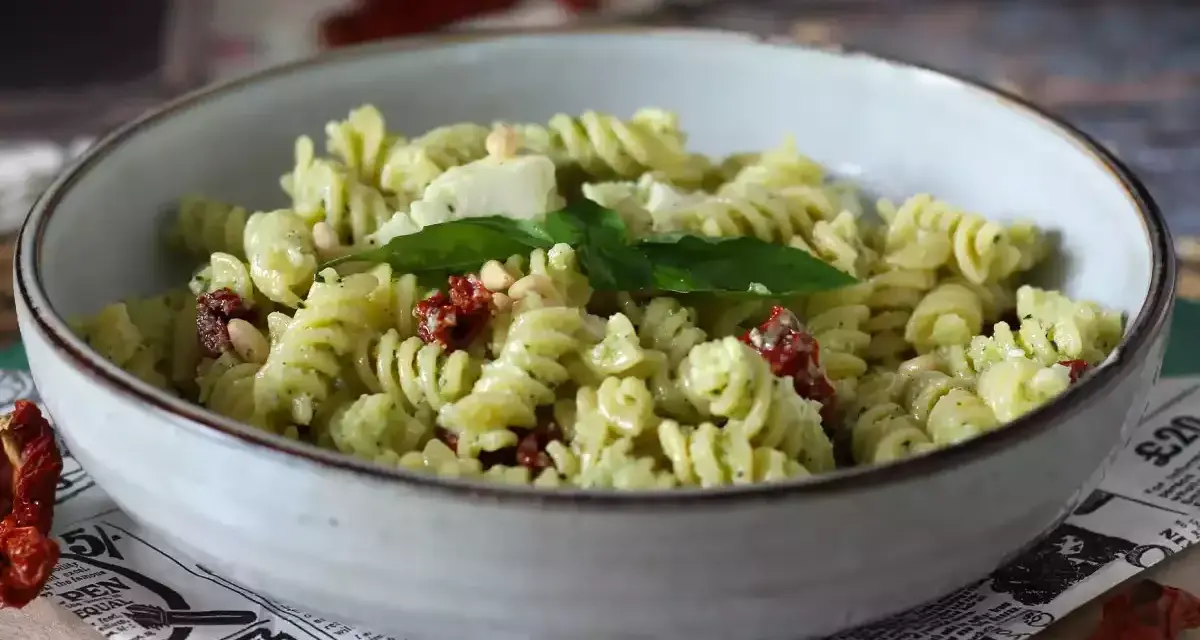 Fusilli con pesto, pomodori secchi, pinoli e basilico fresco. Un piatto di pasta con verdure colorato e saporito.