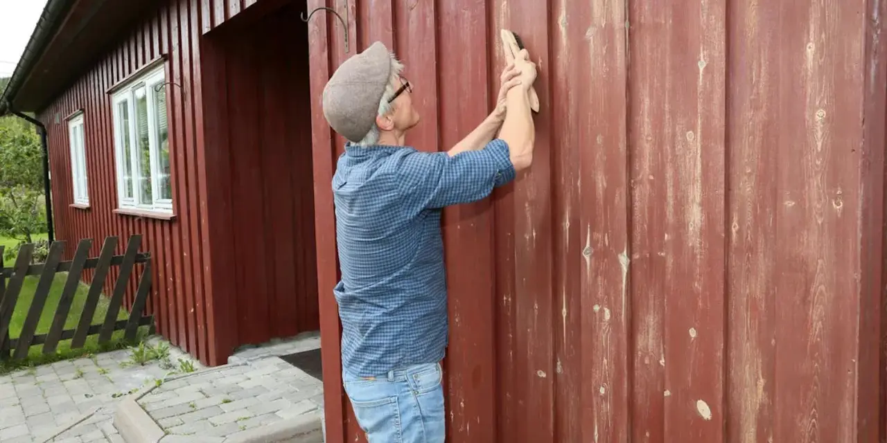 Man slipar fasaden innan målning.