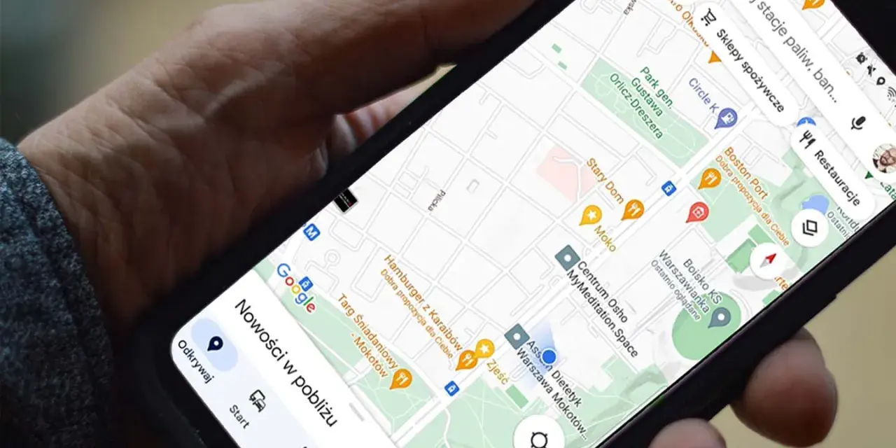Dłoń trzyma telefon z mapą. Aplikacja do udostępniania lokalizacji pokazuje pobliskie restauracje i sklepy.