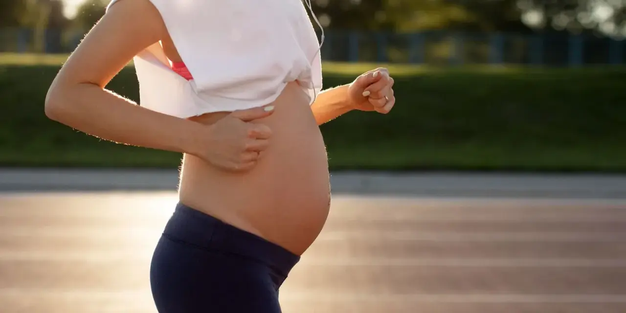 En gravid kvinna springer på en löparbana i solnedgången.