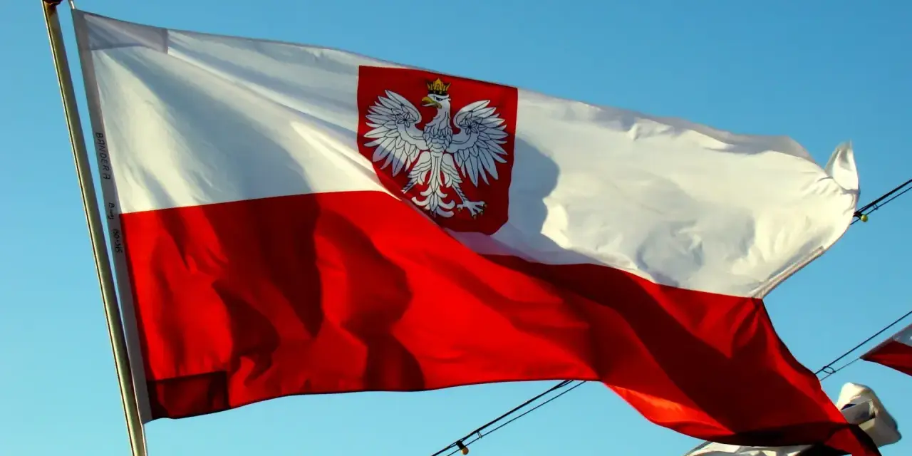 Polska bandera z orłem na tle błękitnego nieba. To symbol dumy narodowej, który powiewa na wietrze.