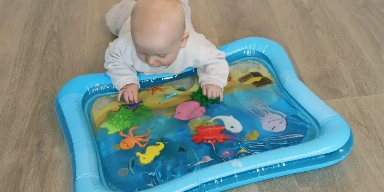 Niemowlę bawi się na macie wodnej dla niemowląt z morskimi stworzeniami.