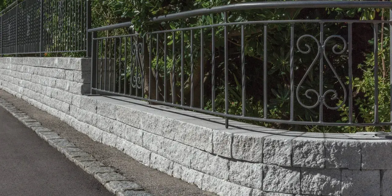 Muro in pietra grigia con ringhiera in ferro battuto, un'ottima idea per muri di recinzione moderni ed eleganti.