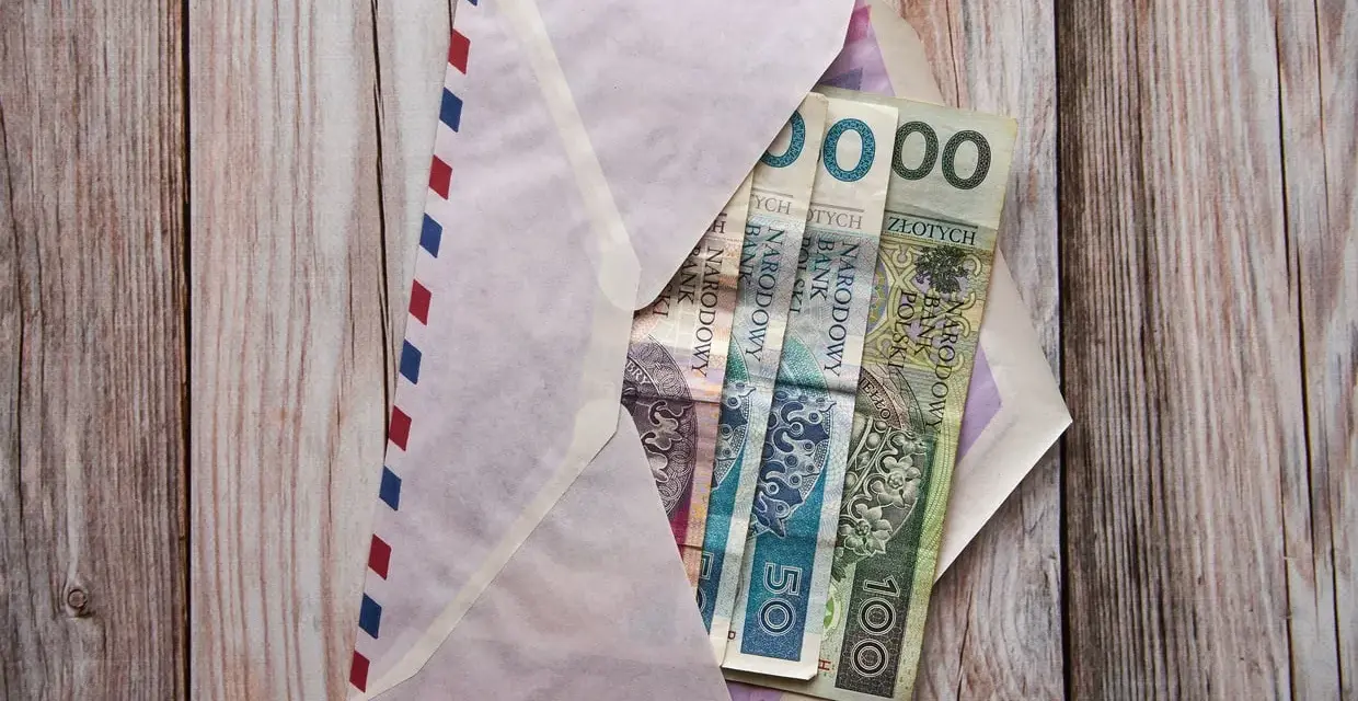 Koperta z pieniędzmi, zastanawiasz się, ile daje chrzestny na komunię? Widoczne banknoty 50 i 100 zł.