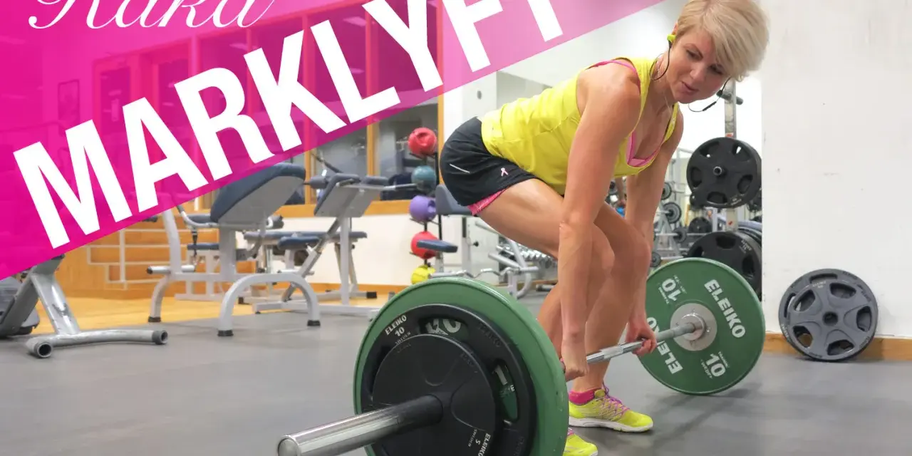 En kvinna utför raka marklyft med en skivstång i ett gym.