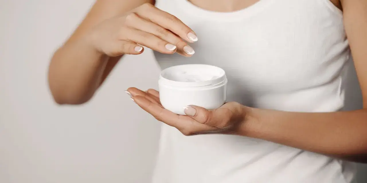 Manos aplicando crema para suavizar la piel y tratar la queratosis pilaris.