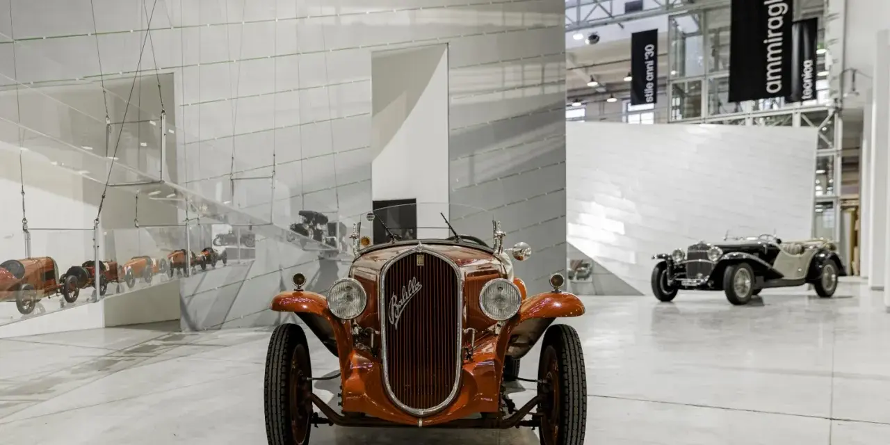 Pomarańczowy Fiat Balilla z 1933 roku na wystawie w Muzeum Fiata w Turynie. W tle inne zabytkowe samochody.