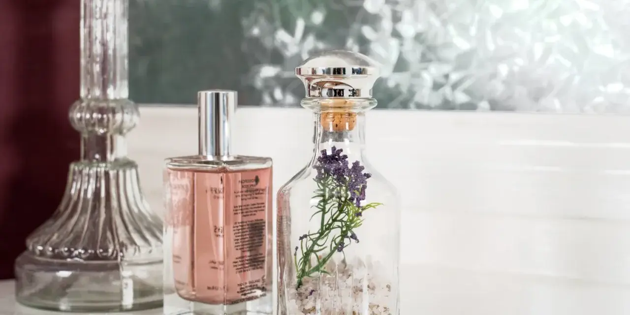 Eleganckie perfumetki męskie w szklanych buteleczkach, jedna z lawendą, obok ozdobnego świecznika.