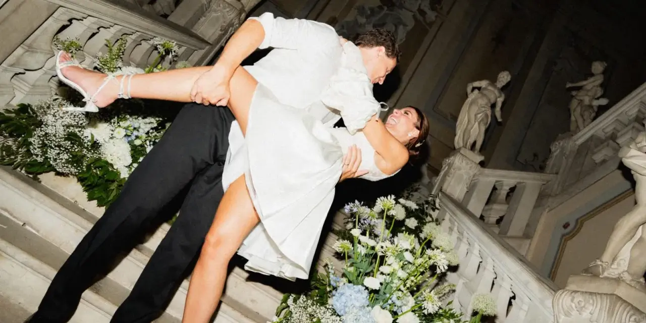 Un couple s'embrasse passionnément sur un escalier orné de fleurs, un moment clé pour réussir son mariage.